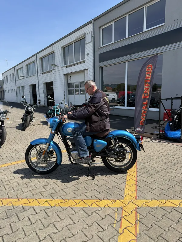 Jezdec na modré motorce Royal Enfield před GARAGE