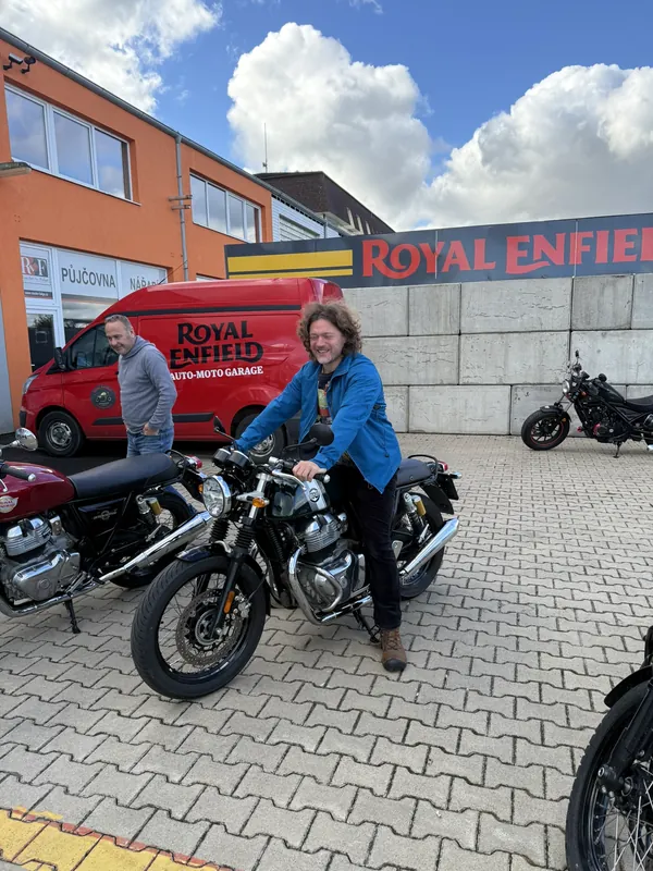 Usměvavá jezdkyně na demo motorce Royal Enfield před GARAGE