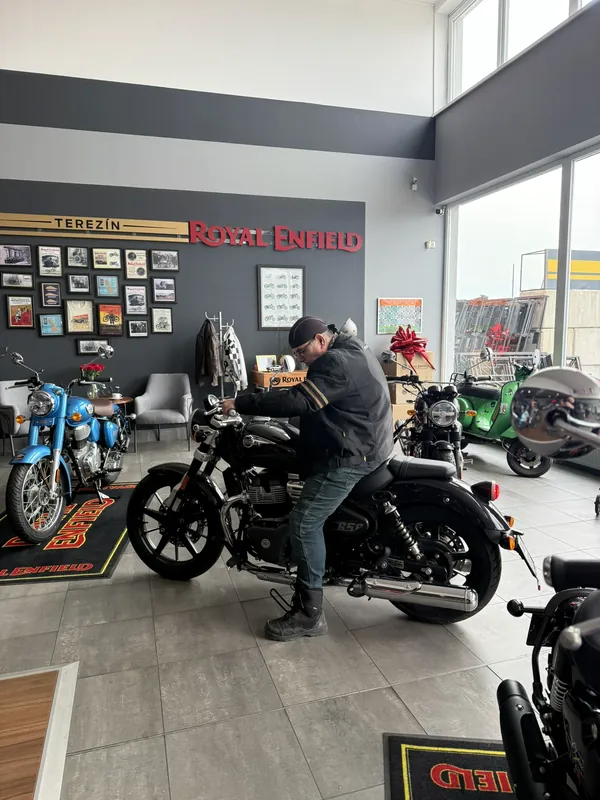 Zákazník zkouší posed na motorce Royal Enfield ve showroomu