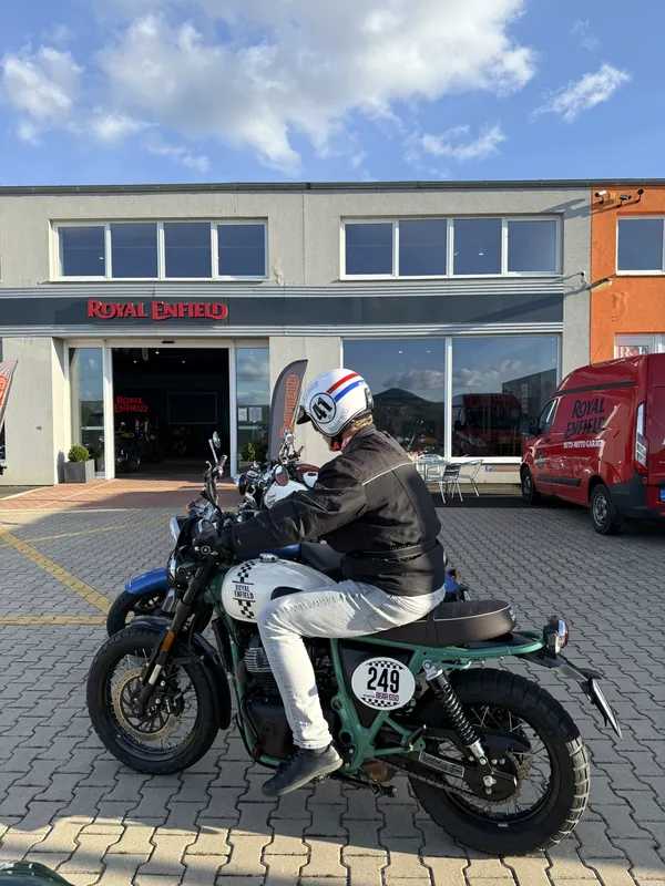 Jezdec v přilbě startuje demo jízdu před Royal Enfield GARAGE