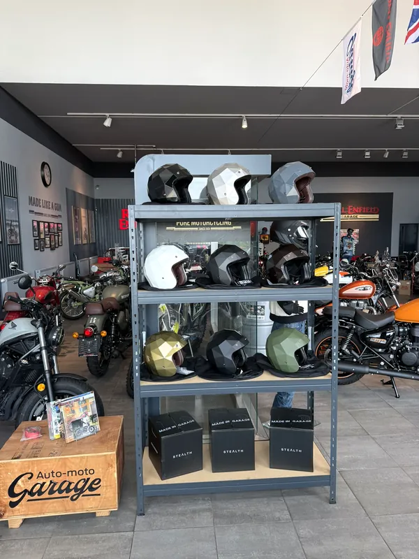 Regál s přilbami Royal Enfield ve showroomu GARAGE