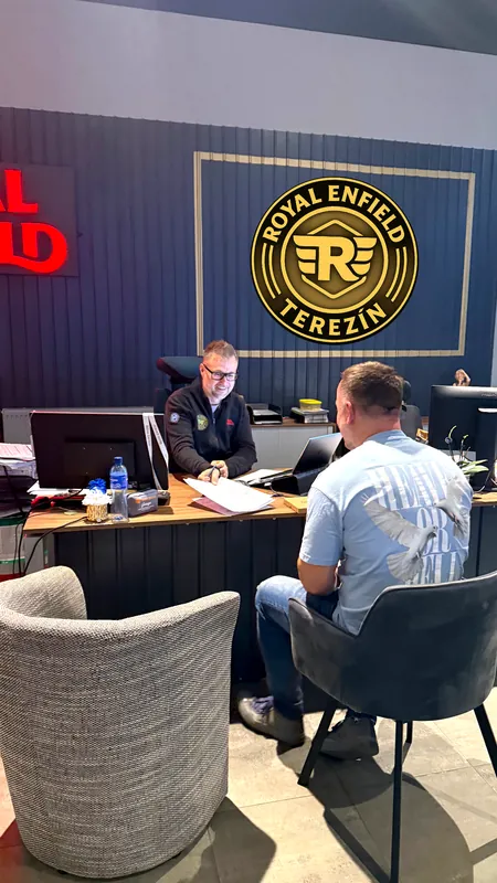 Zákazník s prodejcem u stolu v Royal Enfield GARAGE