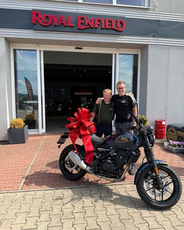Předání nové motorky Royal Enfield s mašlí před GARAGE